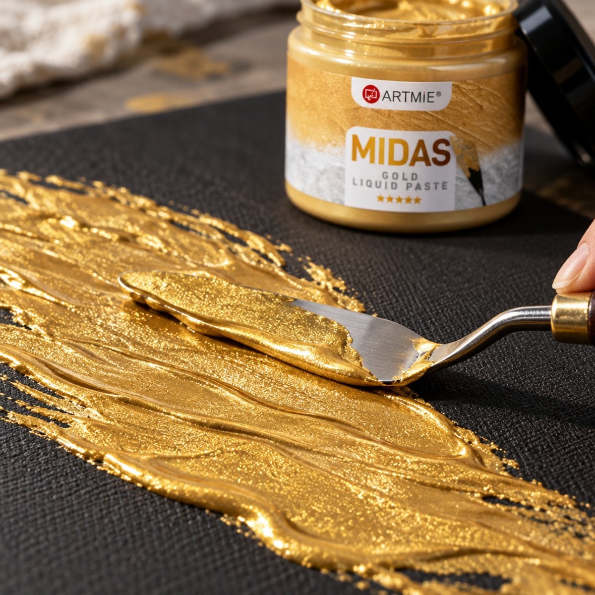 Нанасяне на златна метална паста ARTMIE MIDAS с шпатула върху черно платно — макро